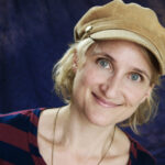 Jill Sobuls smiling while wearing a tab cap and red and black striped shirt