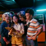 Group of diverse teenagers enjoying a retro arcade game, having fun indoors with friends.